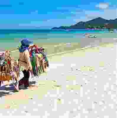 Local Thai seller walking along the beach