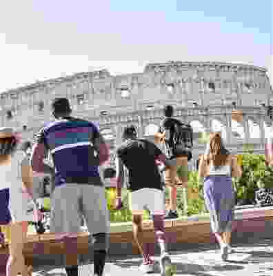 Travellers stepping over a small wall to get to the Rome Colosseum.