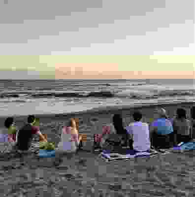 Group of travellers watching the sunset over Seminyak beach.