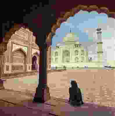 Women traveller sat under the arches looking at the Taj Mahal.