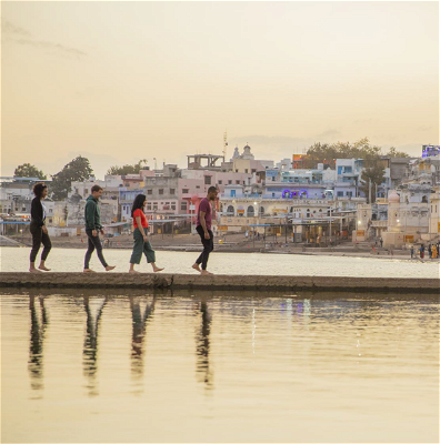 Four travellers along a walkway out in the ocean in Pushkar.