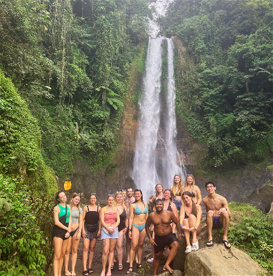 Group of travellers smiling under a waterfall in Lovina.