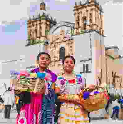 Two local girls smiling in Oaxaca whilst selling their goods.