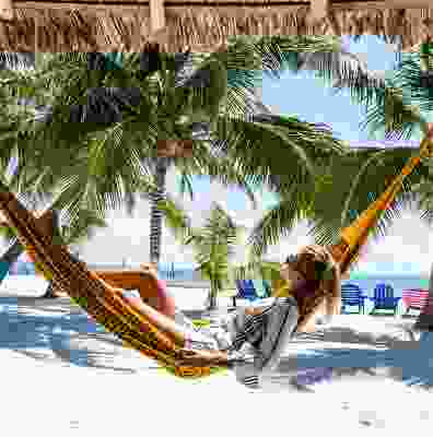 Women traveller relaxing in a hammock on Playa Del Carmen beach.