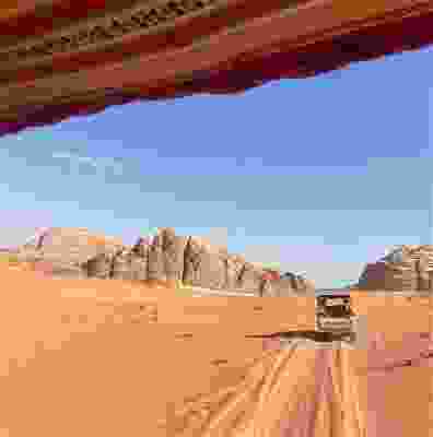 Travellers riding in vehicles through the desert in Wadi Rum.