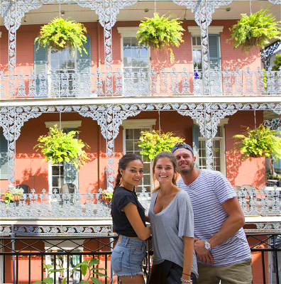 Three travellers smiling in front of decorated pink building in New Orleans.