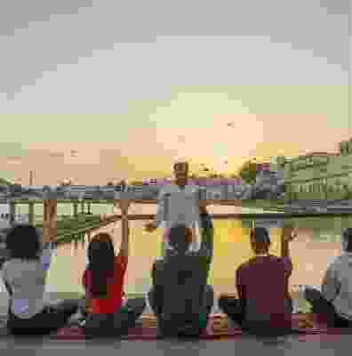 Group of travellers meditating at sunset in front of Pushkar Lake.