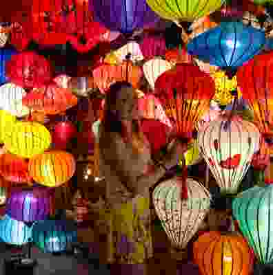 Women smiling in a room full of paper lanterns at the Hoi An markets.