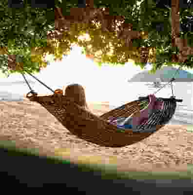 Women sat watching the sunset over the beach in a hammock.