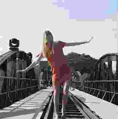 Women walking across a railroad track whilst smiling with her hands in the air.