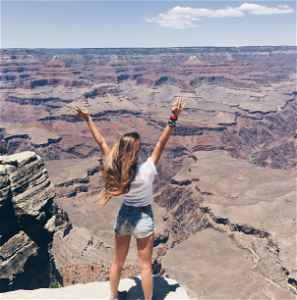 Traveller with hands up looking across the Grand Canyon National Park, United States